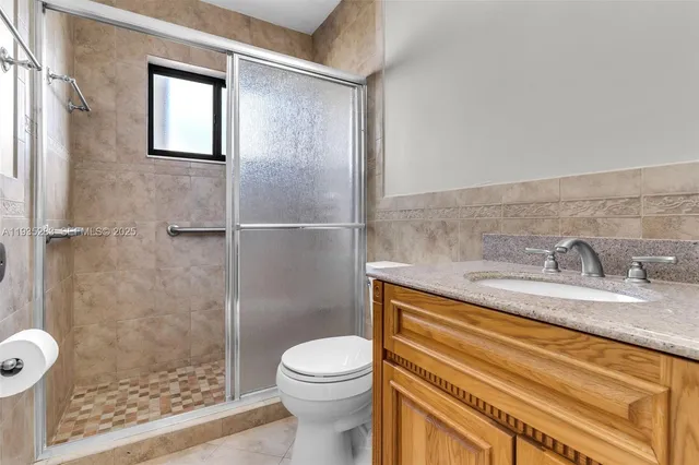 a bathroom with a granite countertop sink toilet and shower