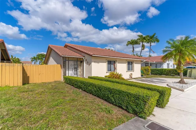 a front view of a house with a garden and trees