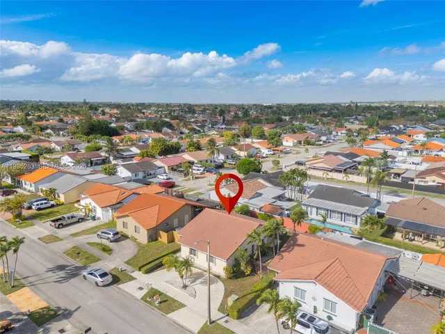 an aerial view of a city with lots of residential buildings ocean and mountain view in back
