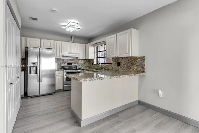 a kitchen with stainless steel appliances granite countertop a refrigerator sink and cabinets