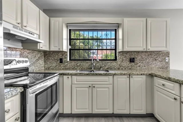 a kitchen with granite countertop white cabinets and white appliances