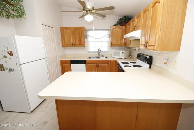 a white kitchen with a sink a refrigerator and a window