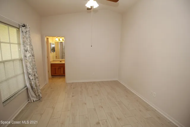 an empty room with chandelier fan and windows