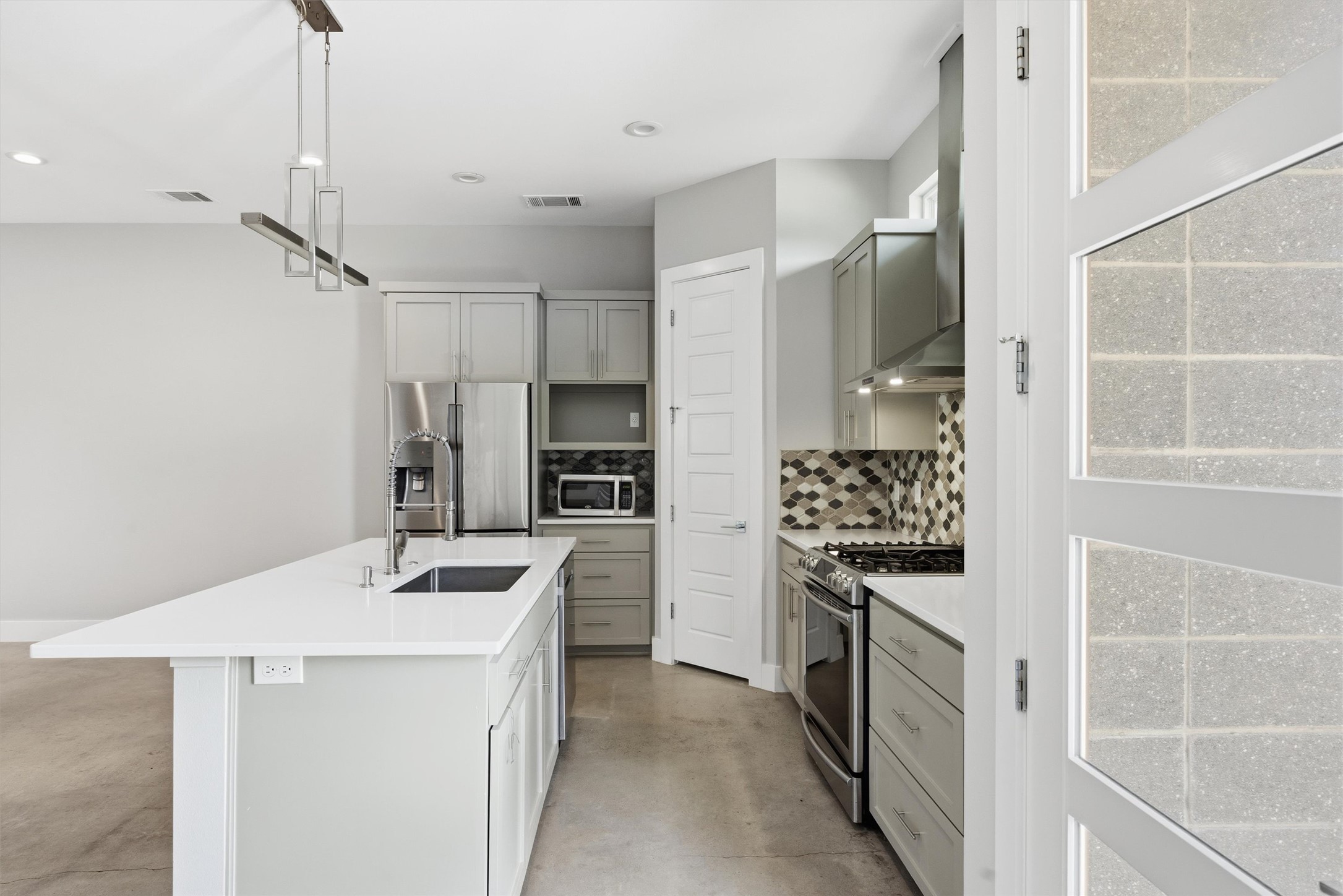 1210 Stobaugh Street, Unit B Austin, TX 78757 - Photo 27 of 40 Modern kitchen with sleek stainless steel appliances and an inviting kitchen island with seating.