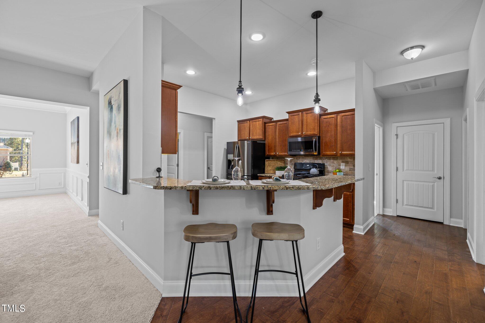 95 Windy Creek Drive Willow Spring, NC 27592 - Photo 12 of 55 a kitchen with stainless steel appliances kitchen island granite countertop a stove a sink a refrigerator and a wooden cabinets