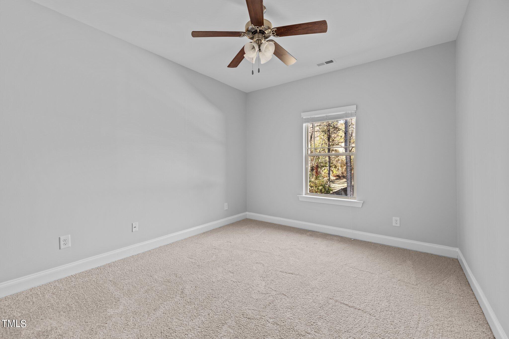 95 Windy Creek Drive Willow Spring, NC 27592 - Photo 27 of 55 an empty room with a window and a ceiling fan
