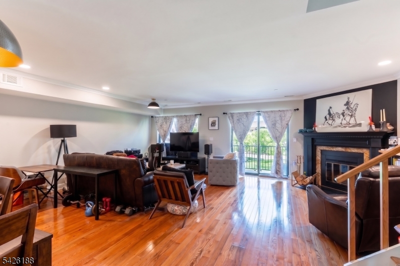 4 Millay Court Teaneck, NJ 07666 - Photo 25 of 32 a living room with furniture a fireplace and a flat screen tv