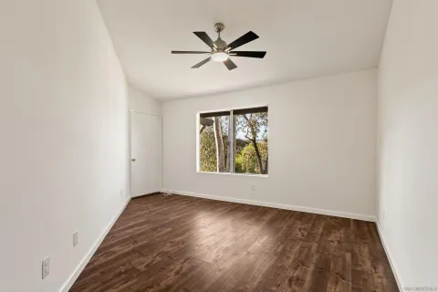 a view of a room with a ceiling fan and wooden floor