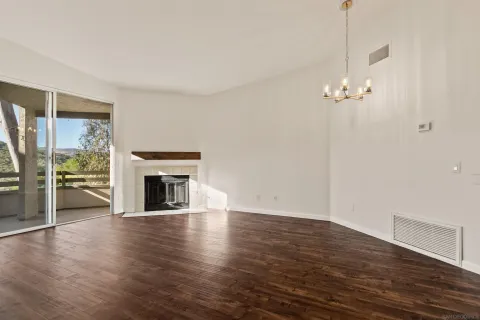 an empty room with wooden floor fireplace and windows
