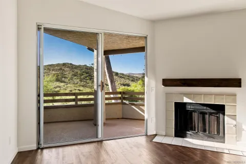 a view of an empty room with wooden floor and a fireplace
