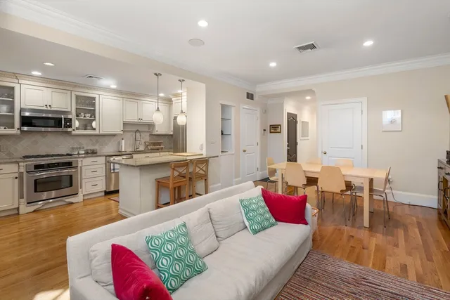 a living room with stainless steel appliances furniture and a kitchen view
