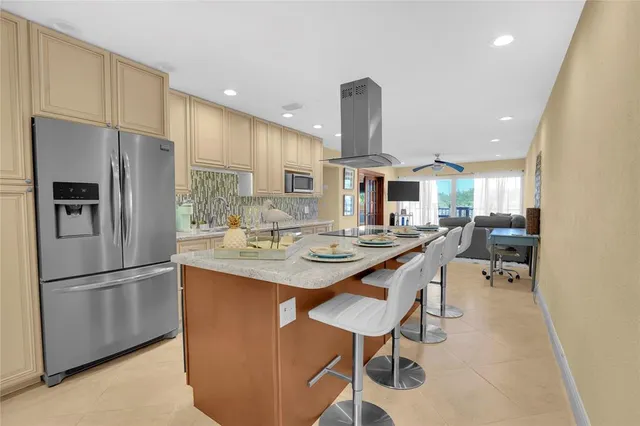 a kitchen with stainless steel appliances kitchen island granite countertop a sink a refrigerator and chairs