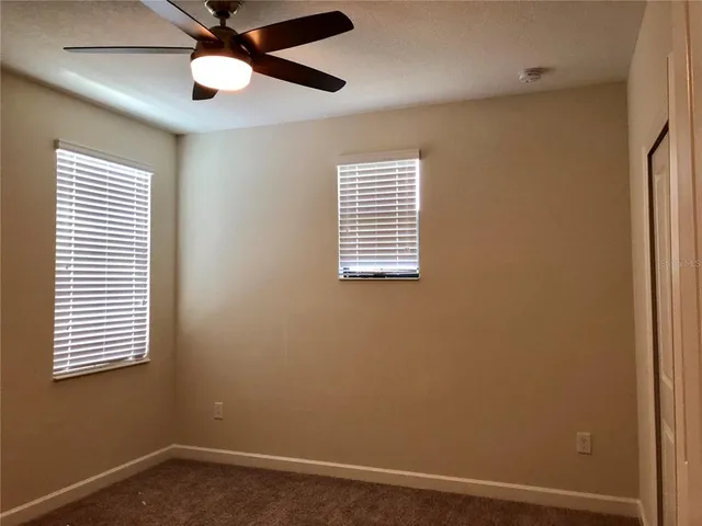 an empty room with windows and fan