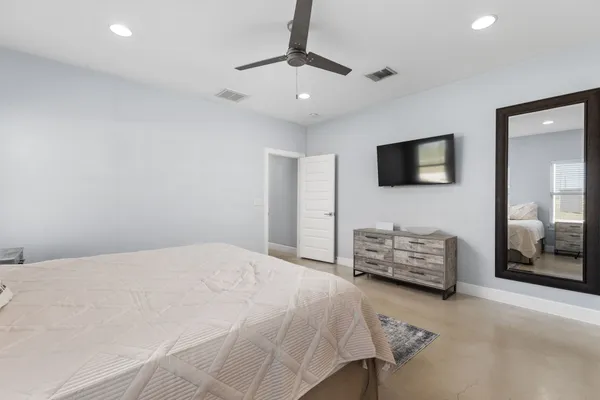 a spacious bedroom with a bed a dresser and a window