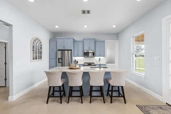 a kitchen with granite countertop a stove top oven a sink a dining table and chairs with wooden floor