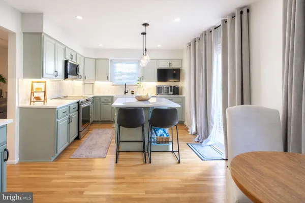 a kitchen with stainless steel appliances kitchen island granite countertop a refrigerator a stove a sink dishwasher and white cabinets with wooden floor
