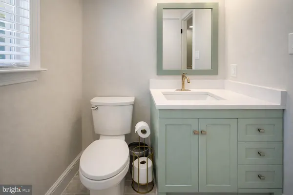 a bathroom with a toilet sink vanity and mirror