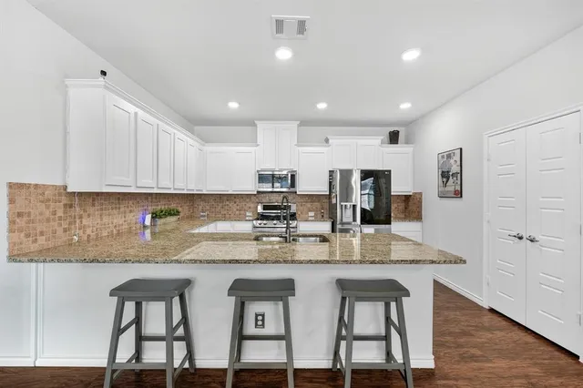 a kitchen with stainless steel appliances granite countertop a kitchen island a stove a table and chairs