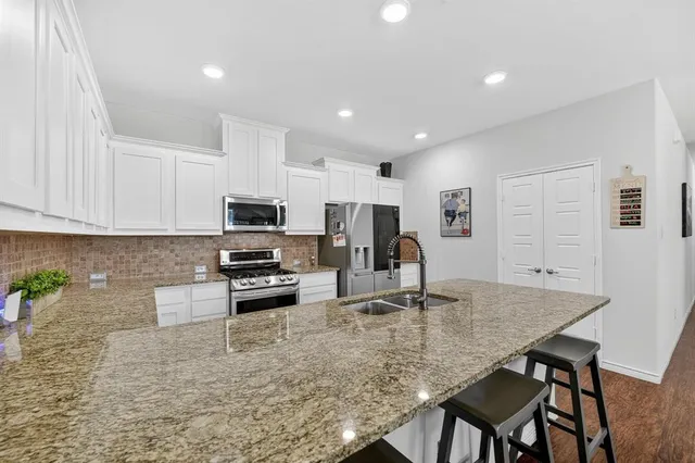 a kitchen with stainless steel appliances granite countertop a stove a sink a microwave a dining table and chairs