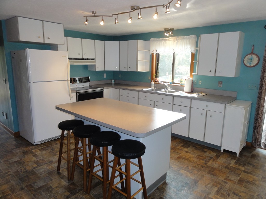 132 Groton Road Shirley, MA 01464 - Photo 6 of 29 a kitchen with stainless steel appliances a table chairs refrigerator and cabinets