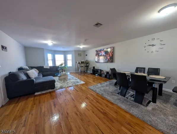 a living room with furniture and a dining table with wooden floor