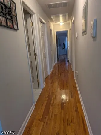 a view of a hallway with wooden floor and staircase