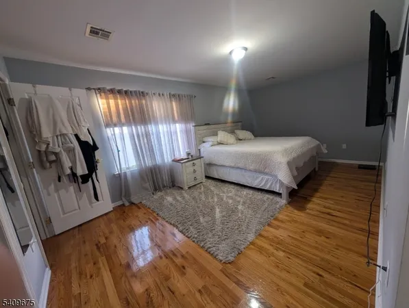 a bedroom with a bed a flat screen tv and window