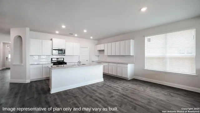 a large white kitchen with kitchen island a sink a stove a refrigerator and white cabinets