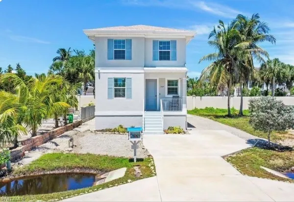 a front view of a house with a yard and potted plants