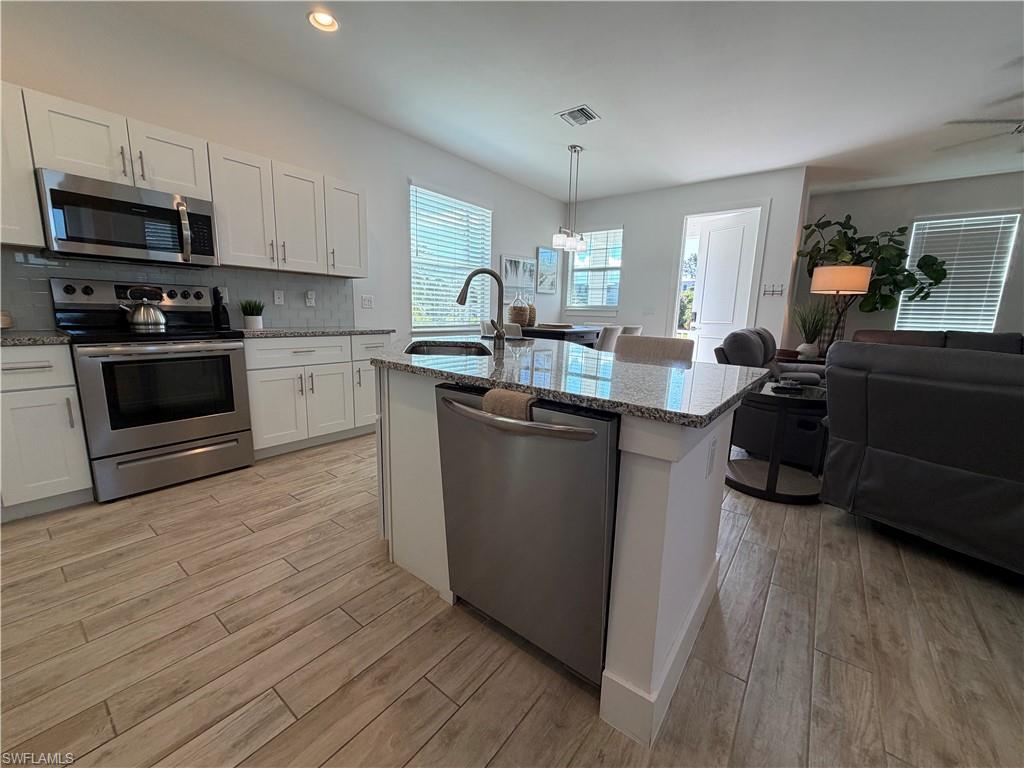1727 Danford Street Naples, FL 34112 - Photo 3 of 15 a kitchen with wooden floors and wooden cabinets