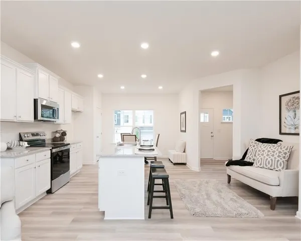 a living room with stainless steel appliances kitchen island granite countertop a stove and a sink