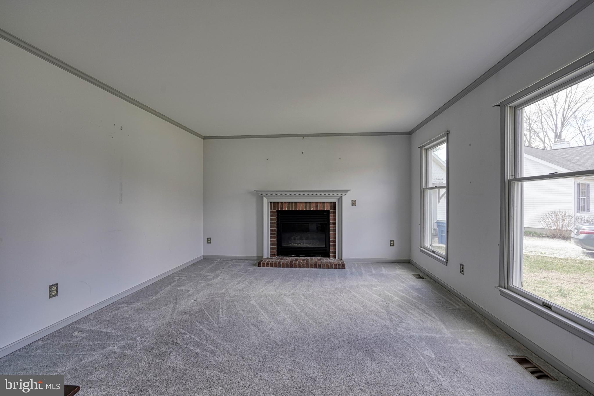 200 Spring Drive Easton, MD 21601 - Photo 16 of 54 an empty room with a fireplace and large windows