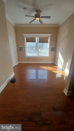 a view of an empty room with window and wooden floor