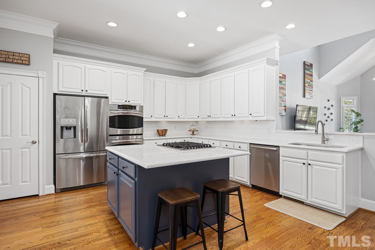 3948 Bentley Bridge Road Raleigh, NC 27612 - Photo 8 of 27 a kitchen with kitchen island white cabinets appliances and wooden floor