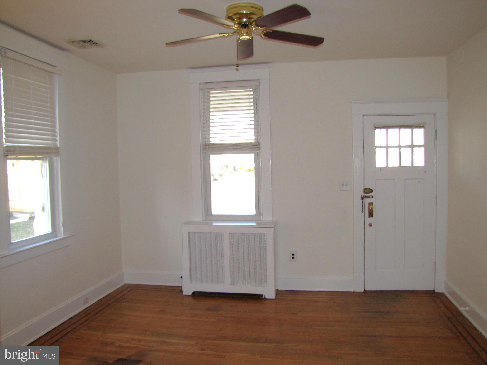 41 Edmondson Ridge Road Baltimore, MD 21228 - Photo 3 of 30 an empty room with wooden floor fan and windows