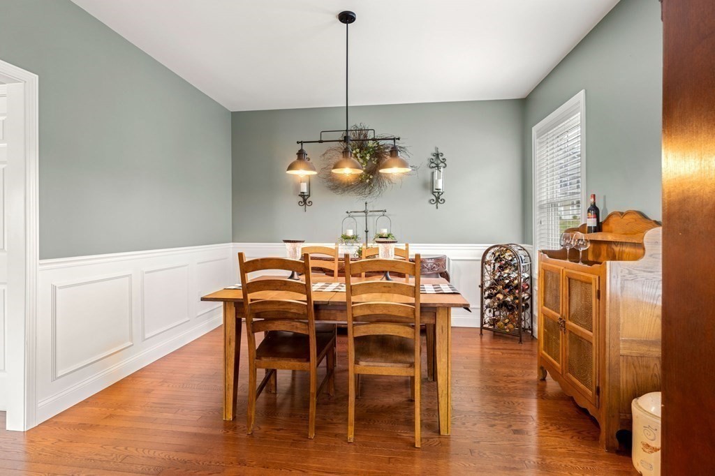 10 Schoolhouse Road, Unit 10 Londonderry, NH 03053 - Photo 11 of 38 a dining room with furniture wooden floor a rug and a chandelier