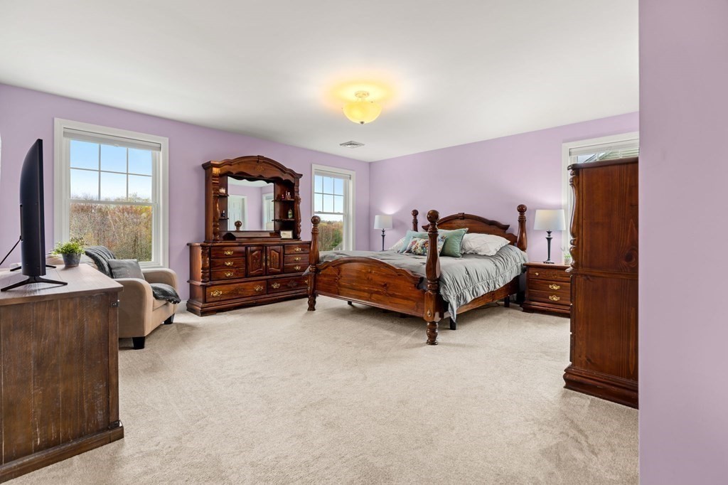 10 Schoolhouse Road, Unit 10 Londonderry, NH 03053 - Photo 19 of 38 a bedroom with furniture and a chandelier