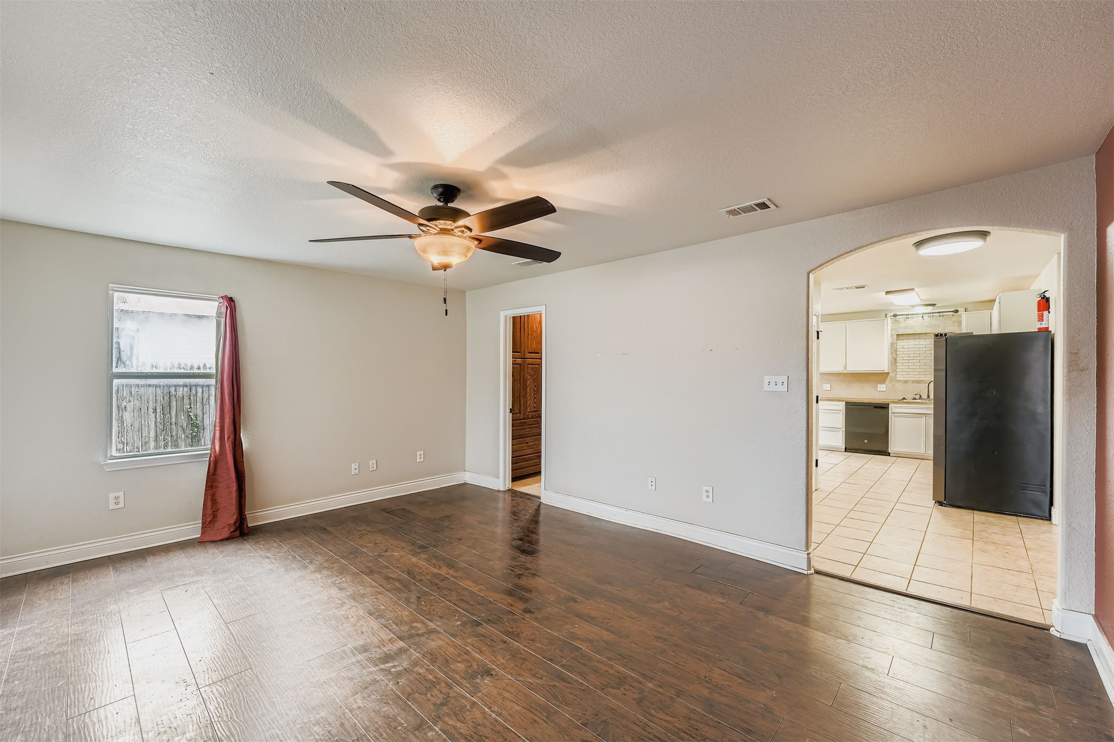 304 South Main Street Elgin, TX 78621 - Photo 11 of 25 Unfurnished room featuring arched walkways, dark wood-type flooring, a textured ceiling, and a ceiling fan