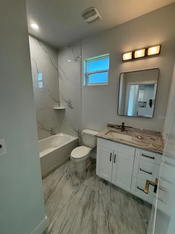 a bathroom with a granite countertop sink mirror vanity and toilet
