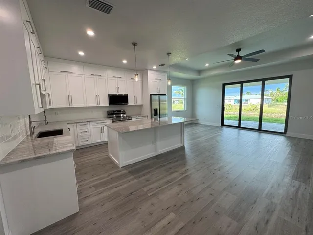 a large kitchen with stainless steel appliances granite countertop a large center island attached withe living room