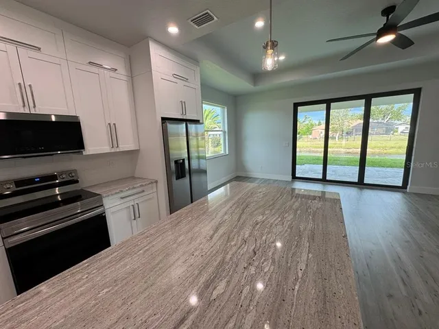 a kitchen with granite countertop a stove a sink and a microwave