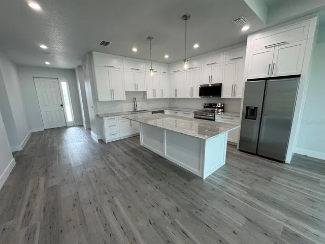 an open kitchen with wooden floor and stainless steel appliances