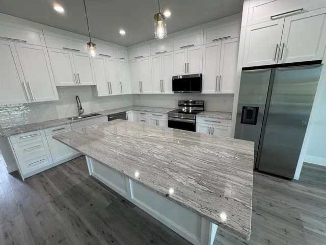 a kitchen with stainless steel appliances granite countertop a sink a stove and a refrigerator