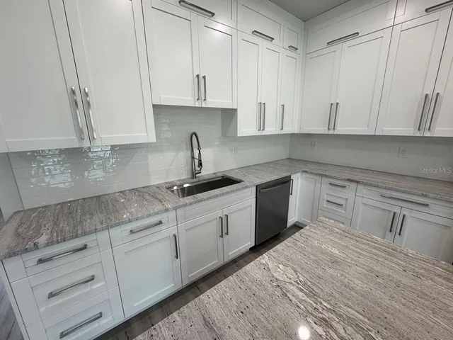 a kitchen with cabinets appliances a sink and a counter top