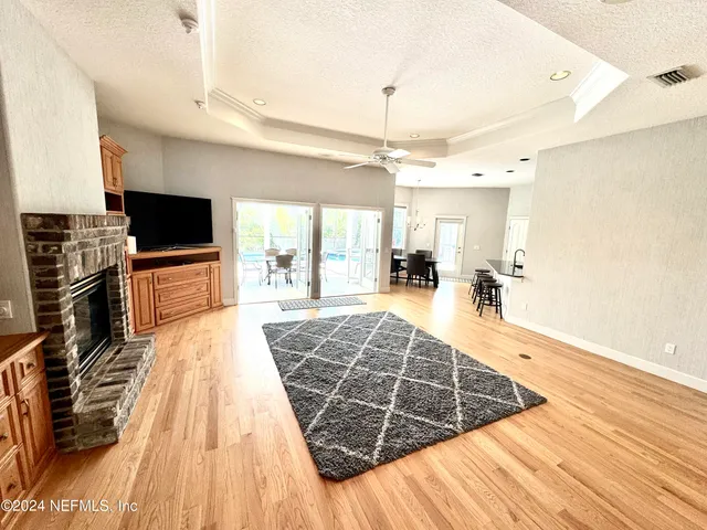 a living room with stainless steel appliances kitchen island granite countertop wooden floor a fireplace and a counter top space