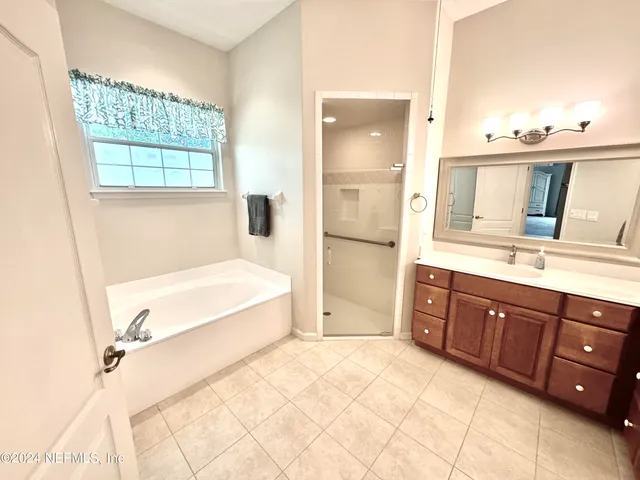 a spacious bathroom with a tub sink and mirror