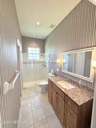a bathroom with a granite countertop sink a toilet a mirror and bathtub