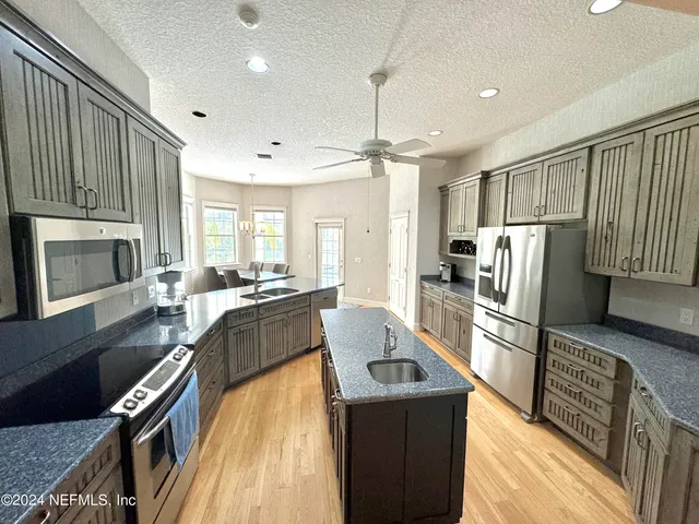 a kitchen with granite countertop a stove top oven a sink dishwasher a dining table and chairs with wooden floor