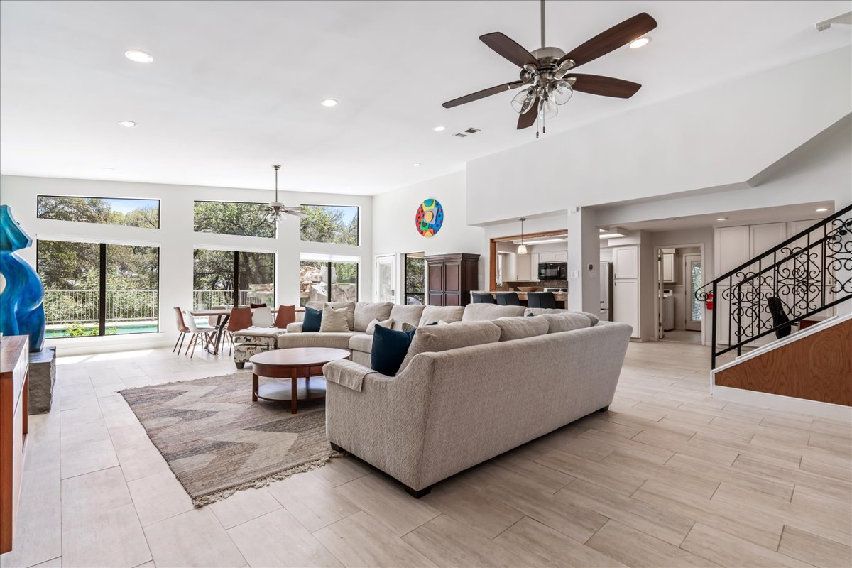 207 Rogers Ridge Street San Marcos, TX 78666 - Photo 5 of 35 Expansive picture windows frame tranquil views of the surrounding natural beauty, while warm wood floors create an elegant, light-filled living space with a sophisticated sense of comfort.