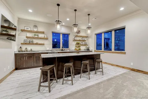 a kitchen with stainless steel appliances kitchen island granite countertop a table chairs sink and cabinets